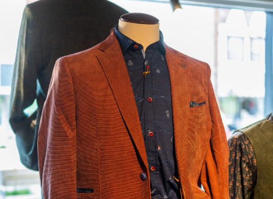 A mannequin with a brown blazer and a colourful dress shirt.