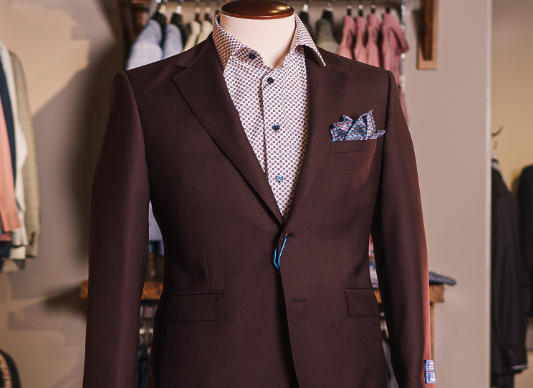 A mannequin with a brown blazer and a colourful dress shirt.